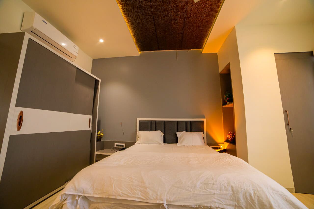 A modern bedroom with a large bed, a wardrobe, a bedside table, and a ceiling light fixture.