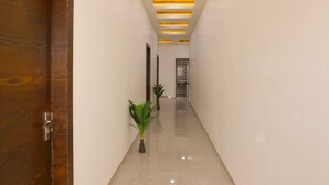 A hallway with a wooden door labeled "109", a polished floor, and a ceiling with recessed lighting. - Hotel KV Pride (Mehekar)