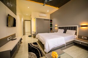 A modern bedroom with a bed, bedside tables, a TV, and a built-in wardrobe. - Hotel KV Pride (Mehekar)