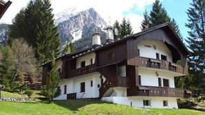 Eine zweistöckige Chalet mit Balkon, vor einer Bergkulisse gelegen.