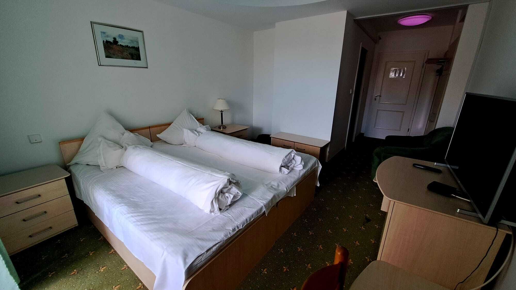 Une chambre d’hôtel avec deux lits, un bureau avec une chaise, une télévision et une porte.