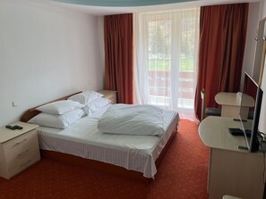 A hotel room with a bed, bedside table, and a desk with a chair. - Hotel Iadolina (Budureasa)