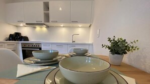 Une cuisine avec des armoires blanches, une cuisinière et un évier. Il y a deux bols sur une table, accompagnés d’une serviette.