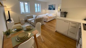 Un espace de vie moderne et compact comprenant un coin repas, un lit et une kitchenette.