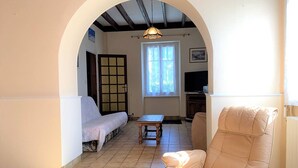 Uma sala de estar com um sofá, uma poltrona, uma mesa e uma televisão.