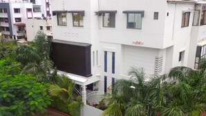 A multi-story residential building with a white facade, multiple windows, and a visible entrance.