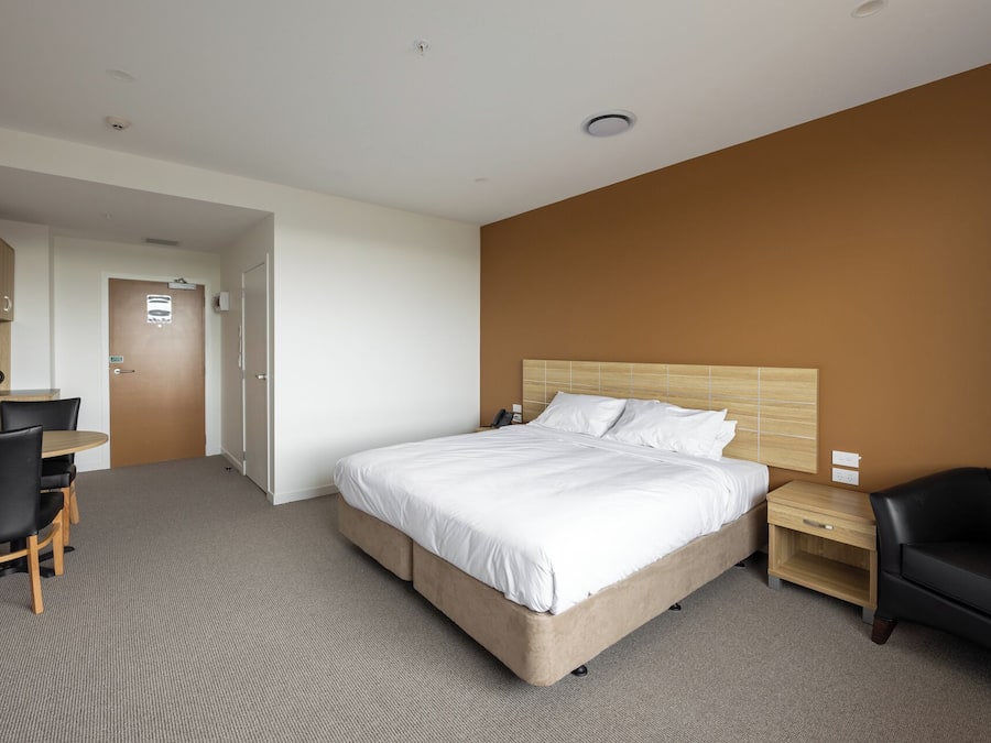 Una habitación de hotel con una cama grande, un escritorio, una silla y un armario.