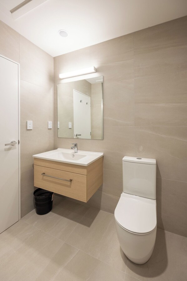A modern bathroom with a white sink, a mirror, and a toilet.
