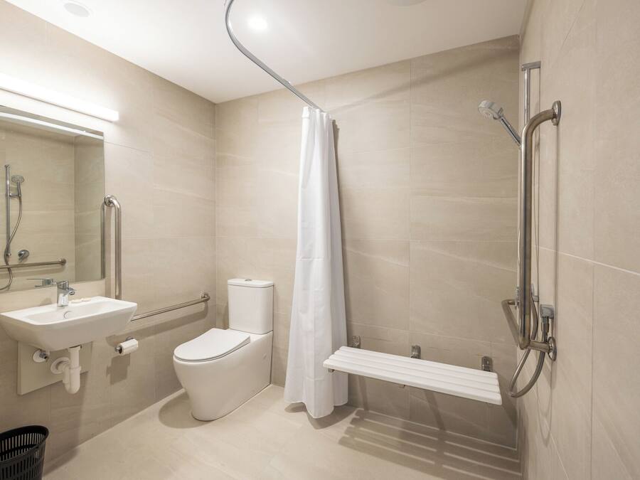A modern bathroom with a shower, toilet, sink, and a mirror.