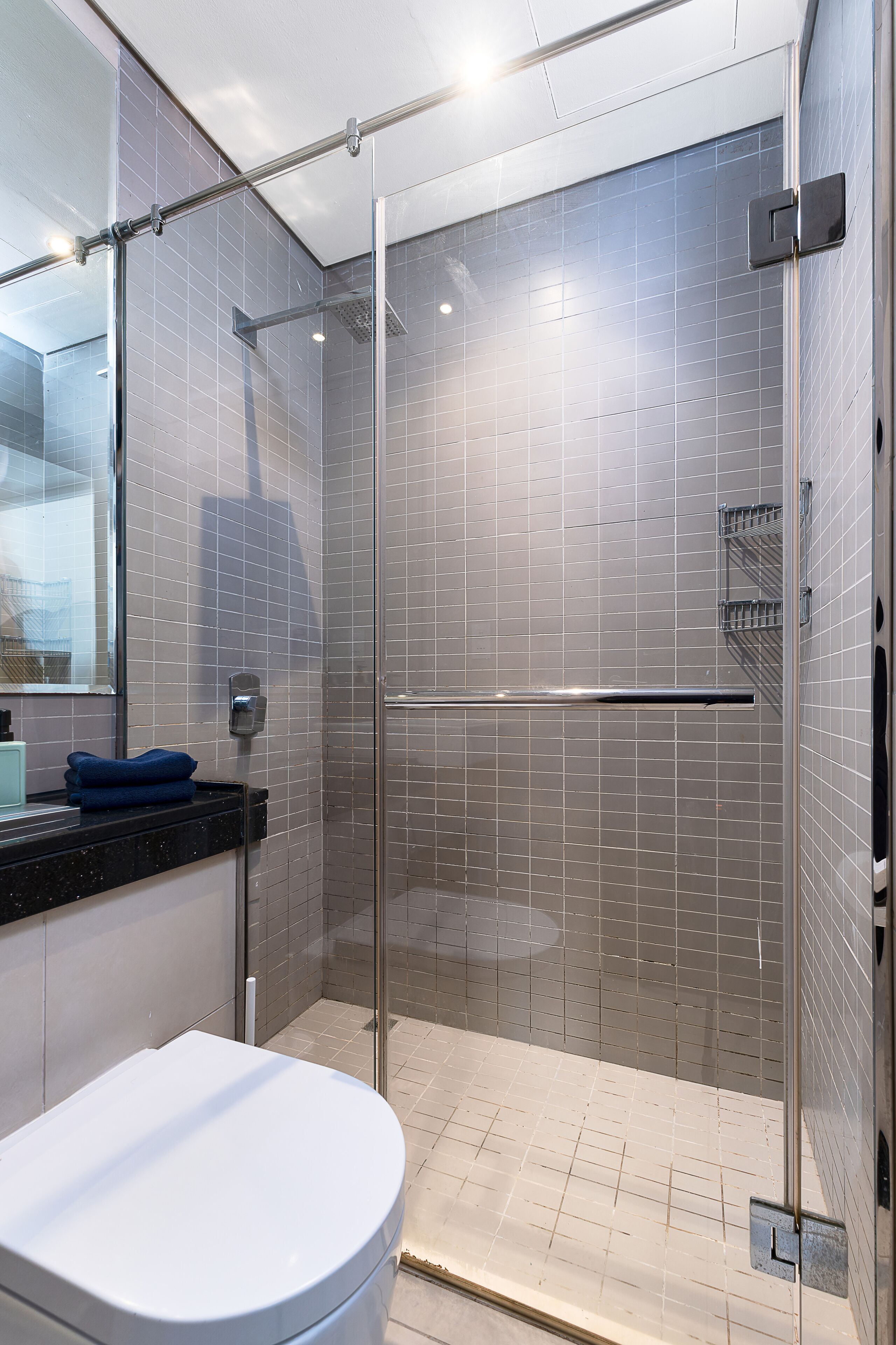 Un baño moderno con ducha cubierta por vidrio, inodoro blanco y salpicadero de azulejos.
