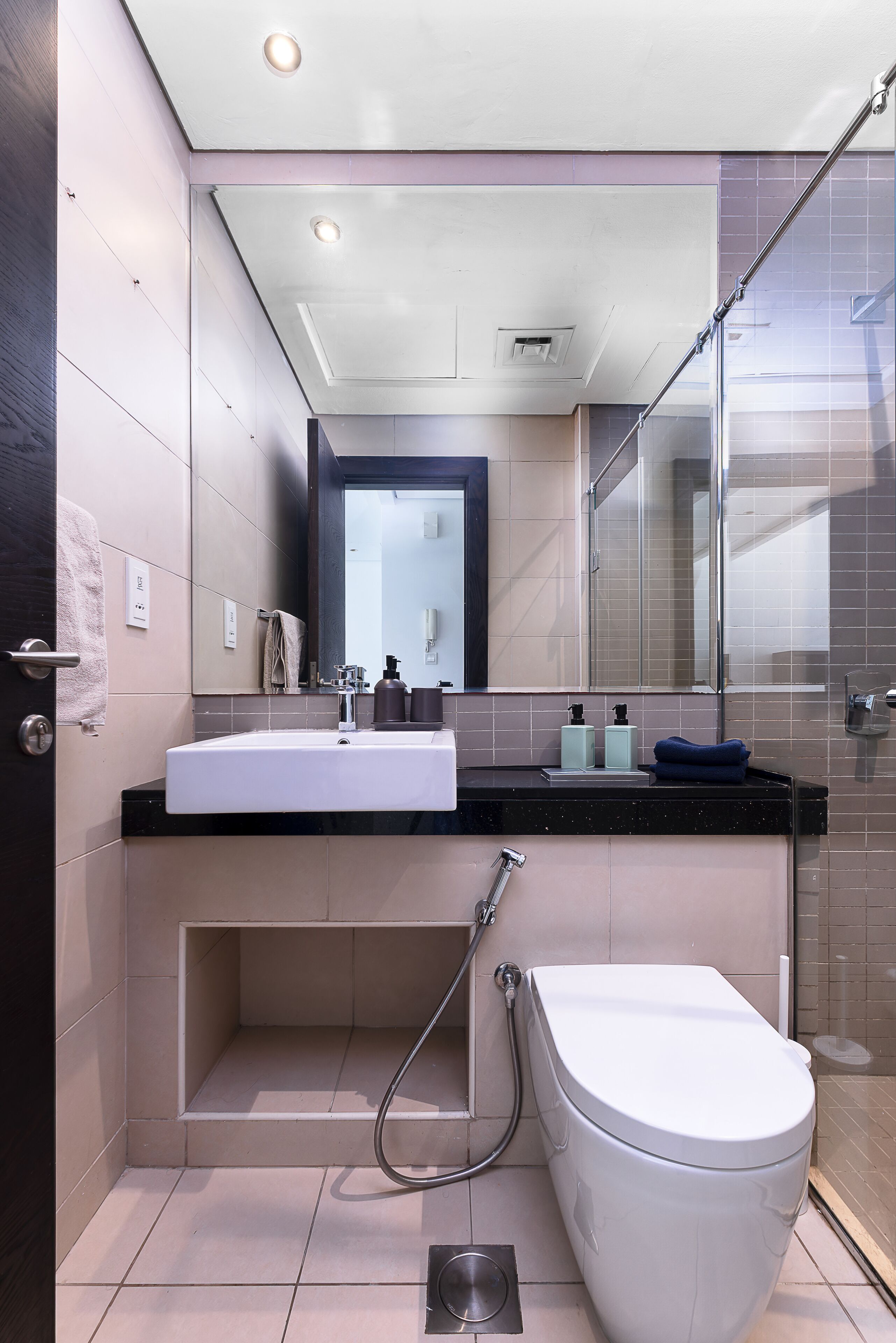 A modern bathroom with a white sink, mirror, and toilet.