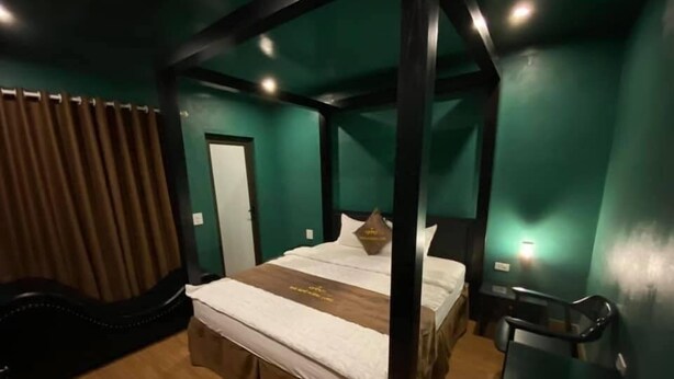 Ein Zimmer mit einem Bett, Holzboden, grüner Wand und einer Tür.