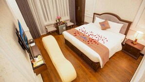 Ein Hotelzimmer mit Bett, Nachttisch, Lampe und einer Bank.