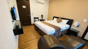 Ein Hotelzimmer mit einem Bett, Nachttischen, einem Fernseher, einem Schreibtisch und einem Stuhl.
