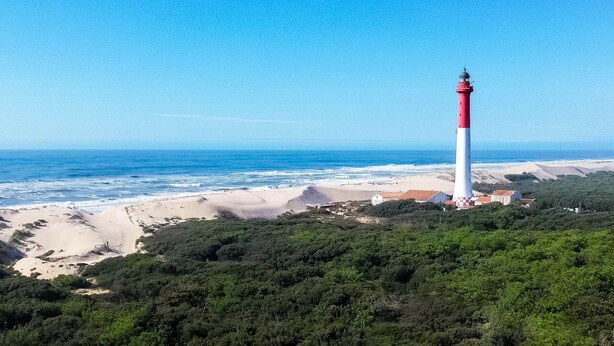 A coastal landscape with a lighthouse, beach, and dense greenery. - 3-room villa 100m from the beach with patio and parking (La Palmyre)