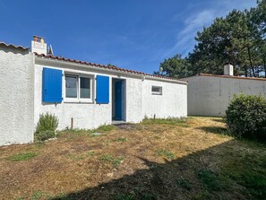 A white building with blue shutters, a small door, and a window.