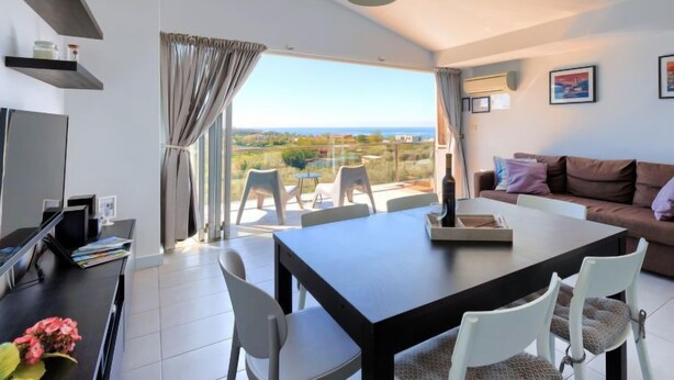 A modern living room with a dining area, large windows, and a view of the landscape. - Apartment Rak by Interhome (Umag/Zambratija)
