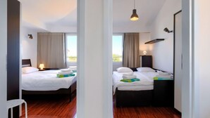 A hotel room with two beds, wooden flooring, a view of the outdoors, and a hanging light fixture. - Apartment Rak by Interhome (Umag/Zambratija)