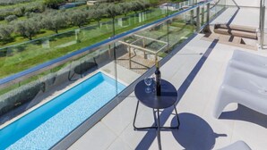 A balcony with a glass railing overlooking a swimming pool and a view of the sea. - Apartment Rak by Interhome (Umag/Zambratija)