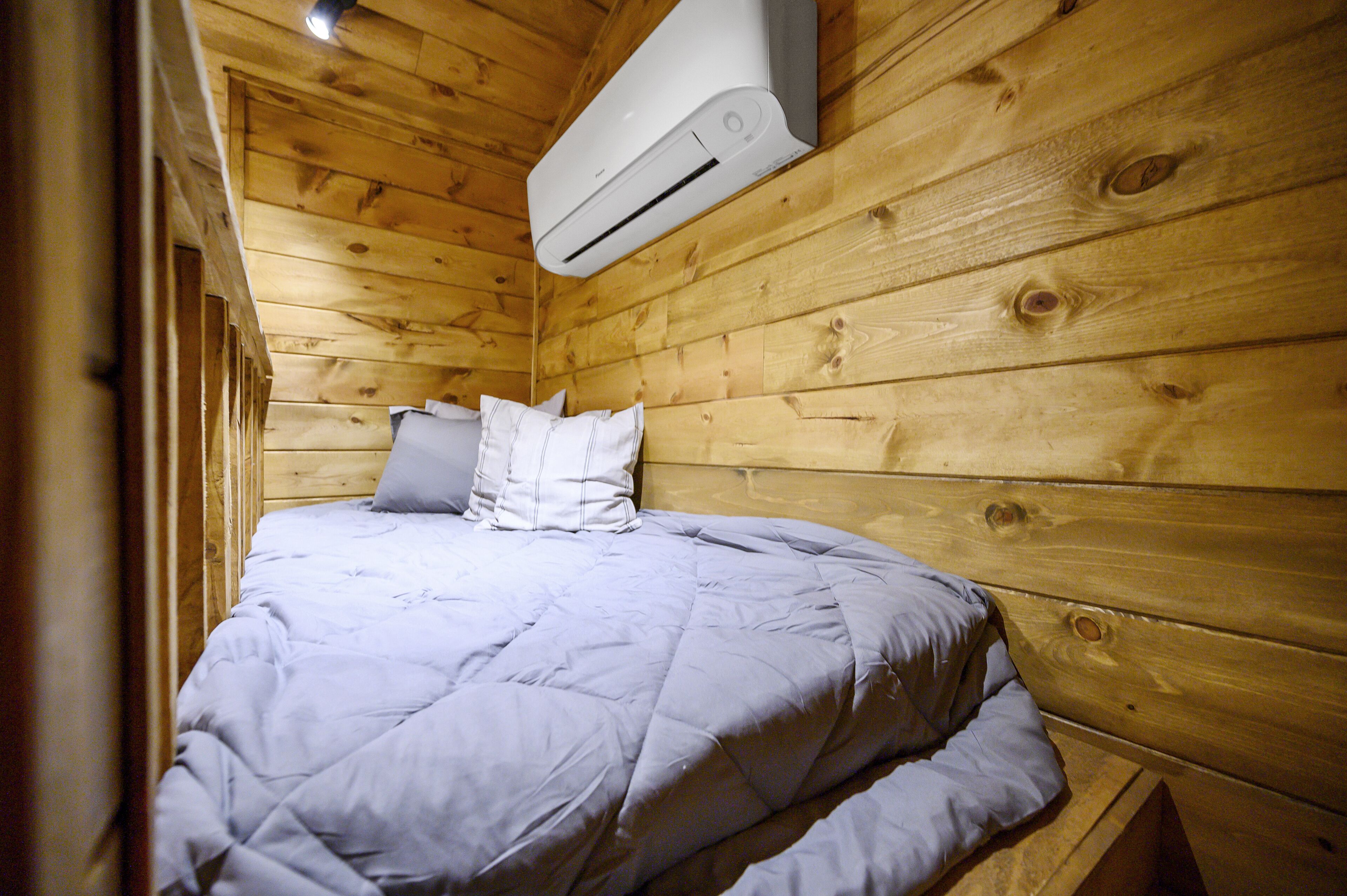A single bed with a grey duvet in a wooden cabin room.