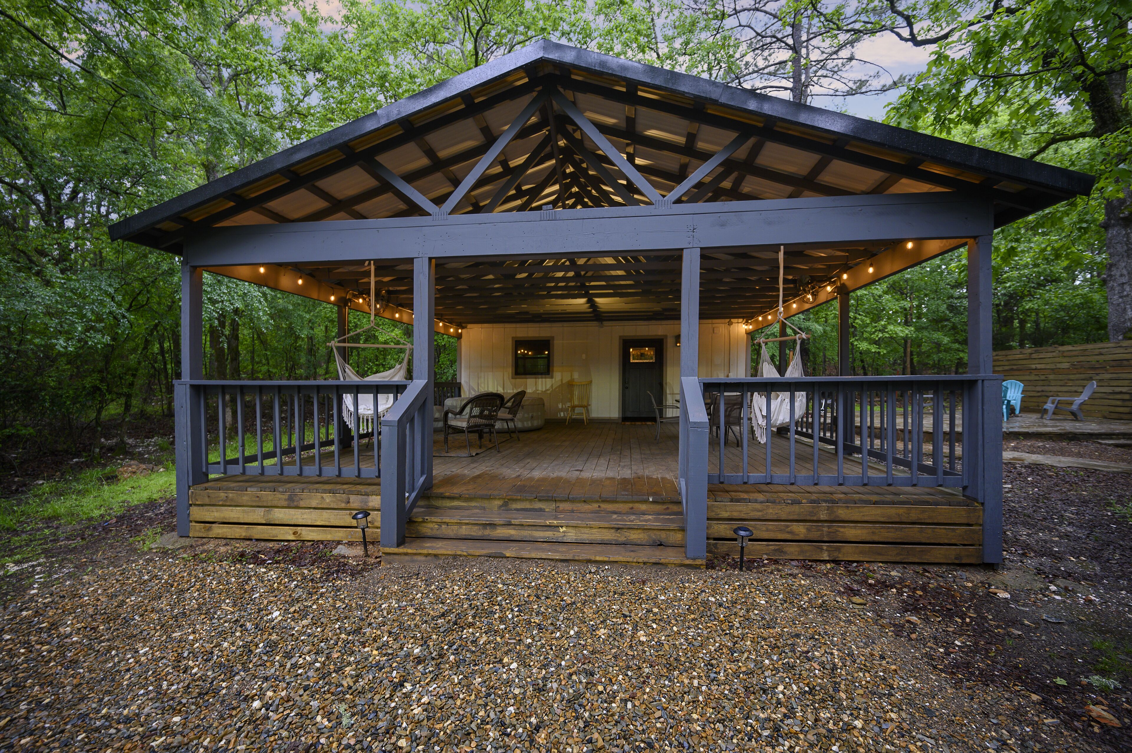 Um pavilhão coberto com deck de madeira, assentos e luzes de corda.
