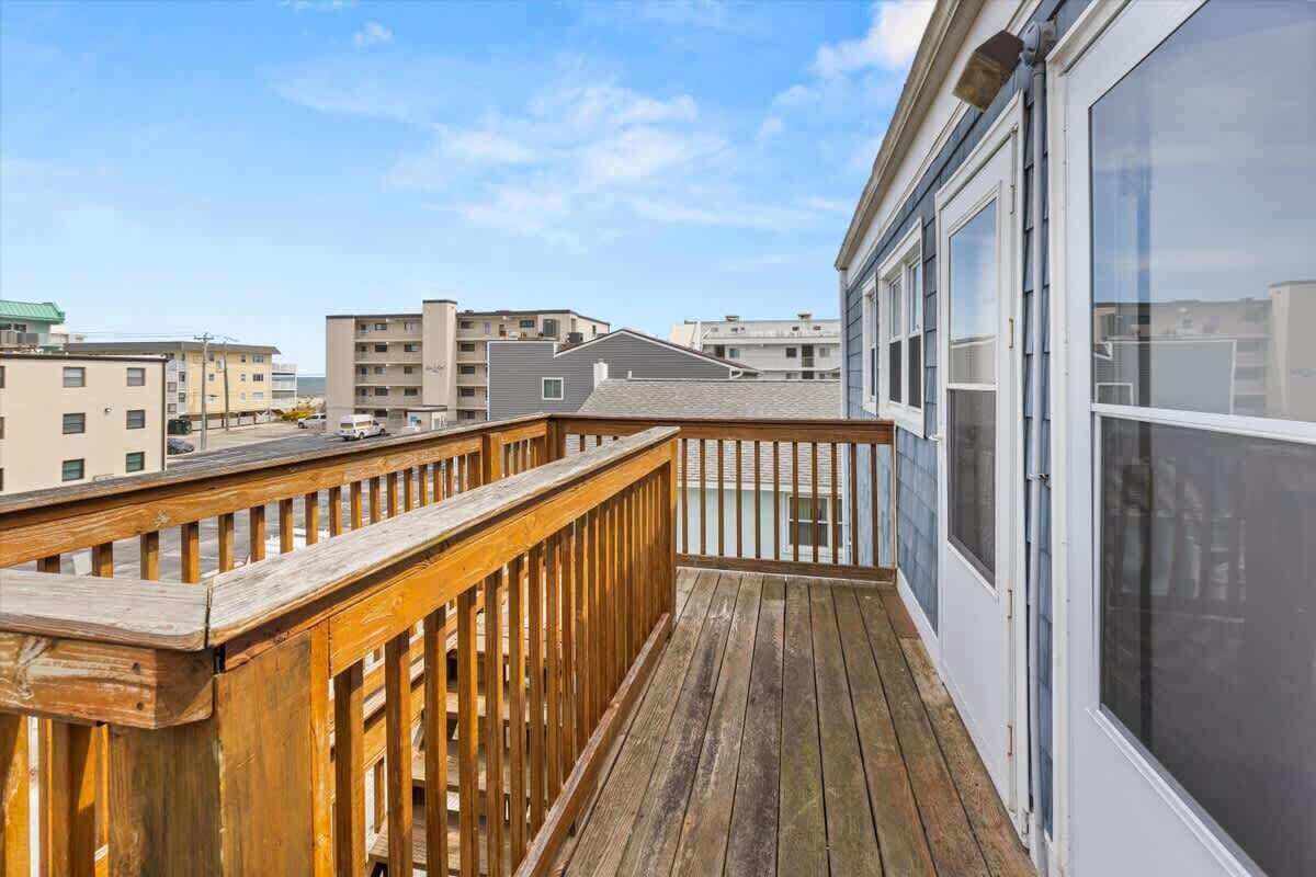 A wooden deck with a glass door leading to a balcony overlooking a residential area.