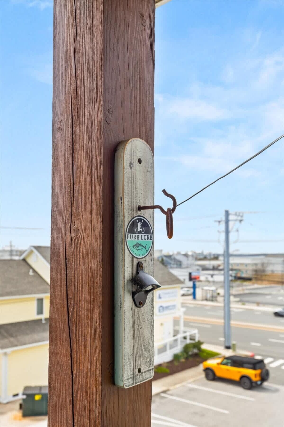 Un poste de madera con una placa metálica que dice 'PURE LURE' y un gancho.