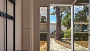 Habitación con puerta de vidrio corrediza que da a un espacio exterior con un sendero de piedra, un árbol y un edificio al fondo.