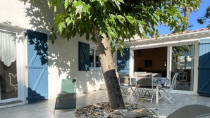 Un patio con un árbol rodeado de grava, una mesa con sillas y una puerta azul.