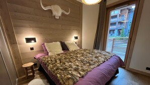 Une chambre moderne avec une tête de lit en bois, un grand plaid en fausse fourrure et un tapis blanc.