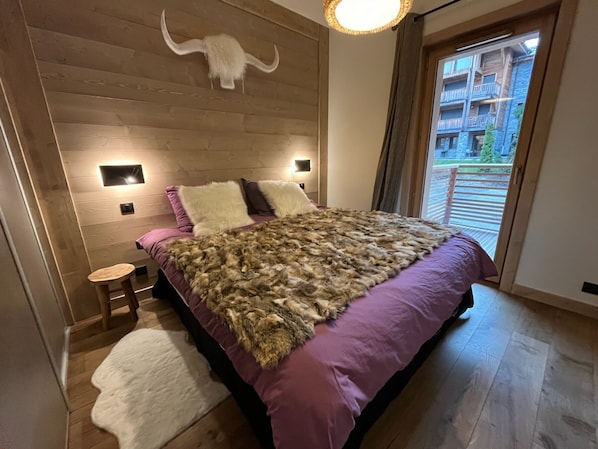 A modern bedroom with a wooden headboard, a large fur throw, and a white rug.