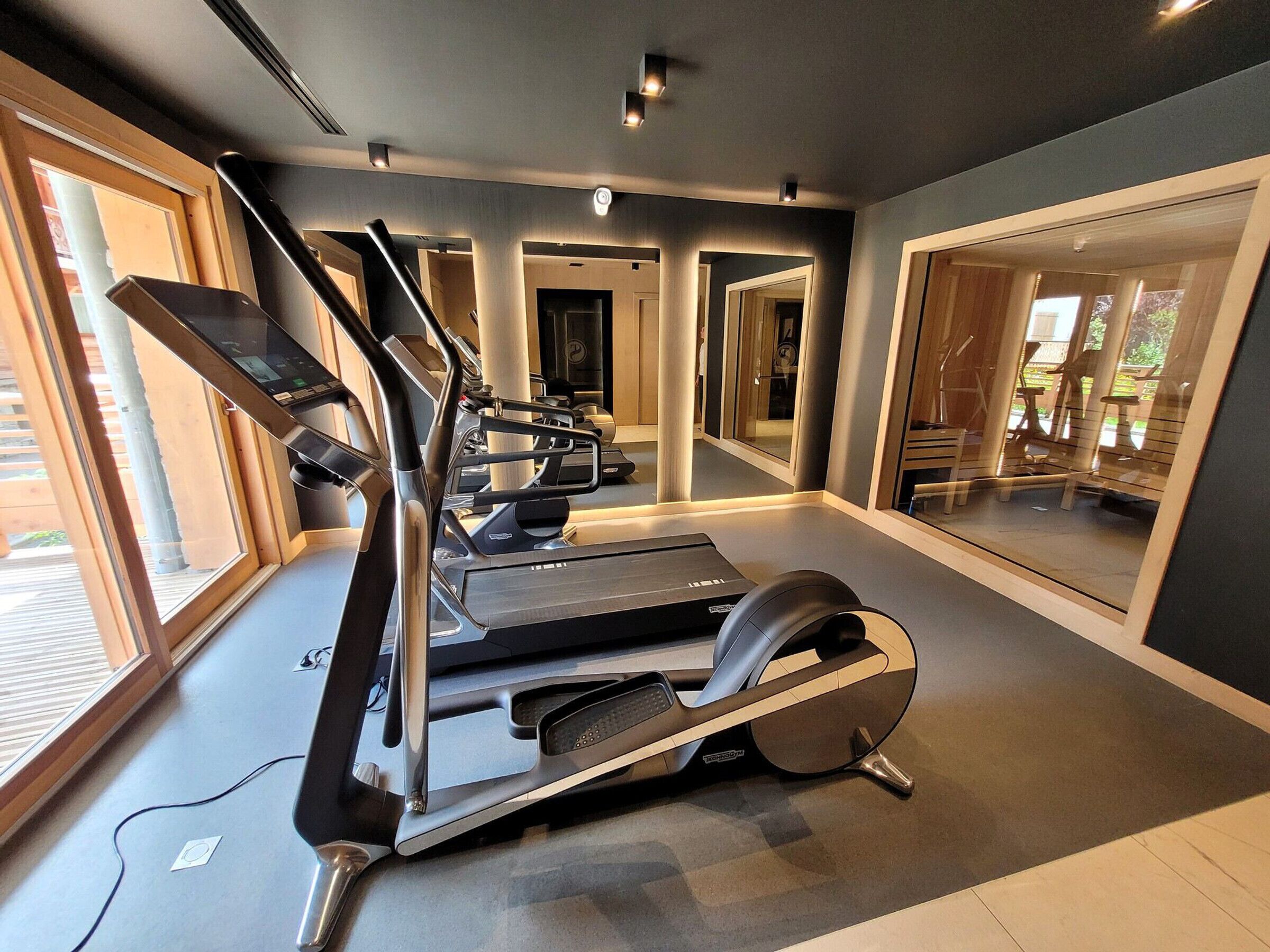 A modern gym with treadmills, a stationary bike, and a rowing machine.