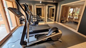 Une salle de sport moderne équipée de tapis de course, d’un vélo d’appartement et d’un rameur.