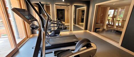 A modern gym with treadmills, a stationary bike, and a rowing machine.