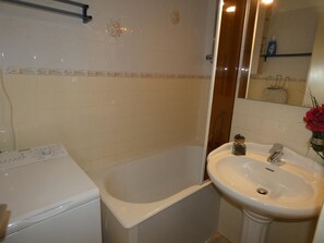 Une salle de bain avec une baignoire, un lavabo et un lave-linge.