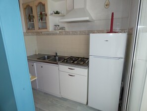 Una cocina con estufa, lavamanos y refrigerador blanco.