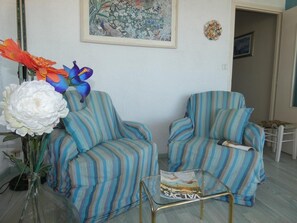 Un soggiorno con poltrone a righe, un tavolino in vetro e un vaso con fiori.