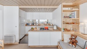 Une cuisine moderne avec des meubles blancs, un îlot central et un plafond en bois.