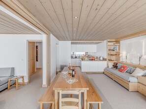 Um interior moderno com uma mesa de jantar de madeira, um sofá e uma área de cozinha.