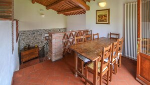 A rustic dining area with a wooden table and chairs, a brick chimney, and a stone wall. - Lovely home in Arezzo with WiFi (Arezzo)