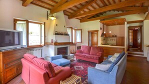 A spacious living room with a fireplace, a television, and a kitchen area. - Lovely home in Arezzo with WiFi (Arezzo)