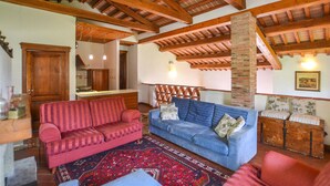 A cozy living room with a red sofa, a blue sofa, and a patterned rug. There is a wooden ceiling with exposed beams and a brick chimney. - Lovely home in Arezzo with WiFi (Arezzo)
