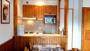 Une cuisine de taille réduite, dotée de meubles en bois, d’un four à micro-ondes et d’un évier.