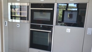 Una cucina con elettrodomestici integrati, tra cui un forno a microonde, forno e un'ampia finestra.