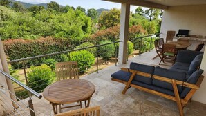 Eine überdachte Terrasse im Freien mit einem Holztisch, einer Couch und Stühlen.