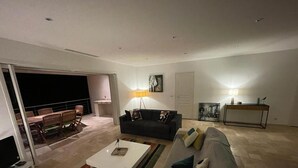 Ein modernes Wohnzimmer mit Sofa, Couchtisch und Fernseher. Ein Balkon mit Tisch und Stühlen ist ebenfalls vorhanden.