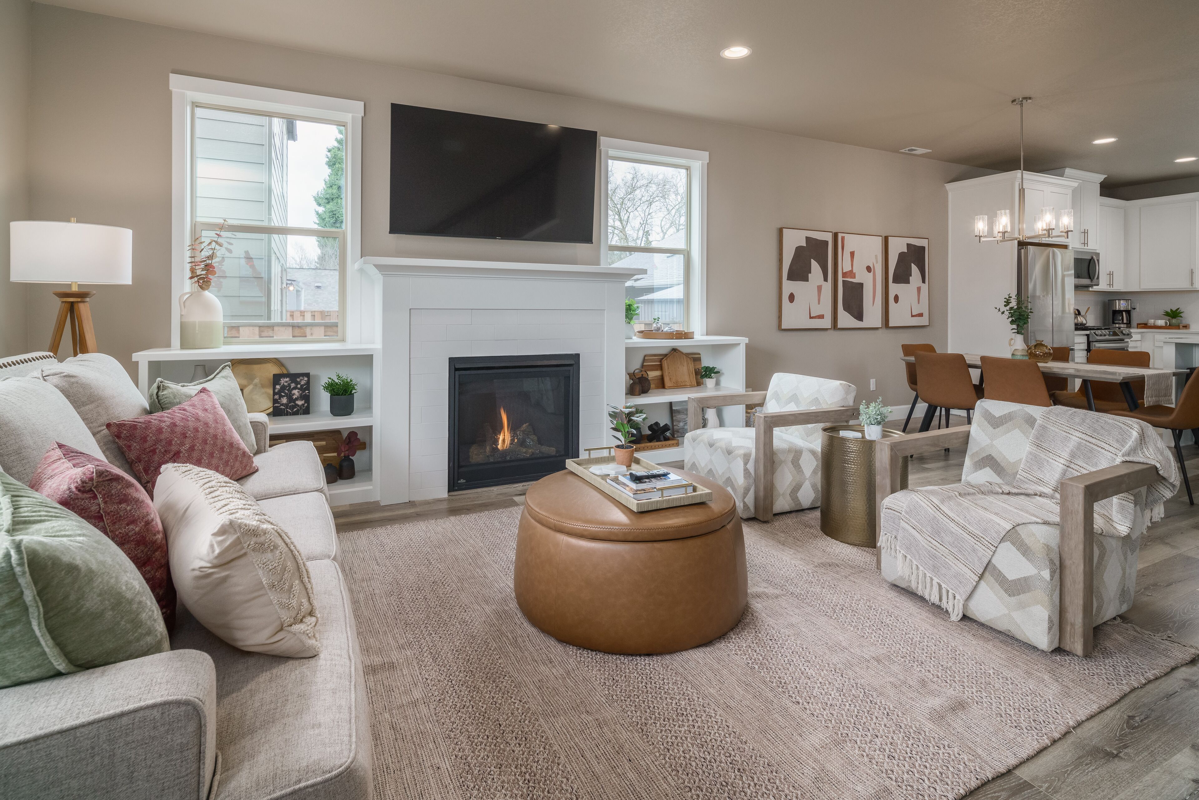 A living room with a fireplace, sofa, ottoman, and dining area with chairs and a table.