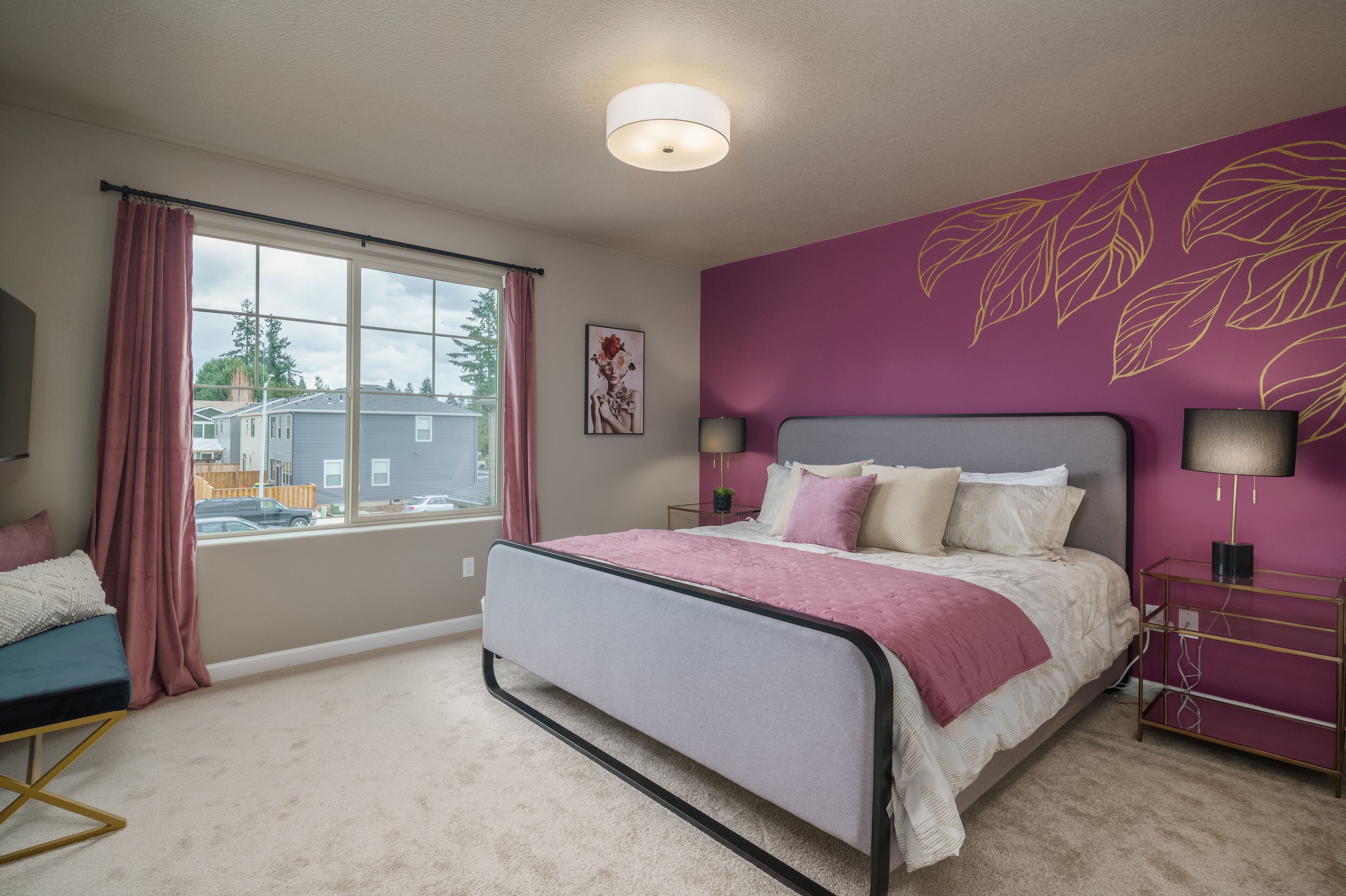 A bedroom with a bed, a nightstand, a lamp, a window with curtains, and a wall with a leaf pattern.