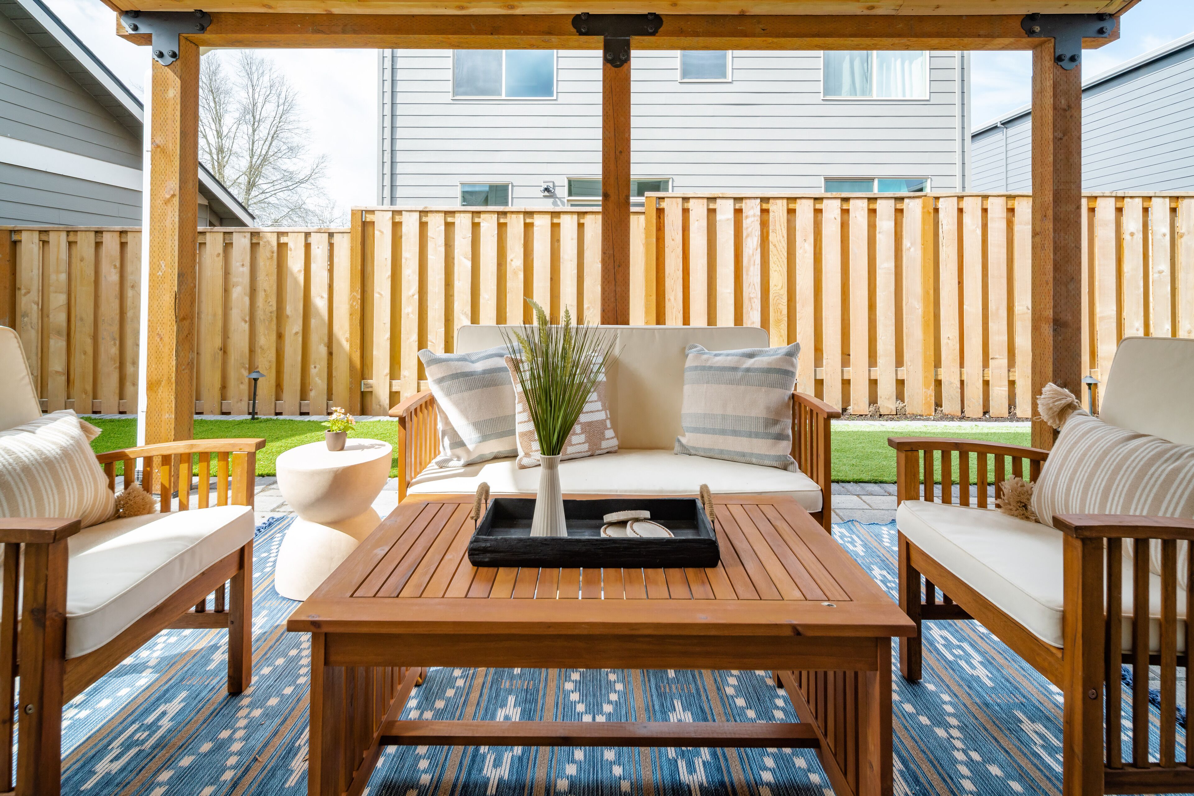 A wooden deck with a sofa and two chairs, a small table, and a tray with a vase and decorative items.