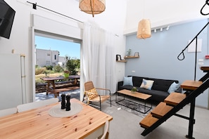 Ein zeitgemäßer Wohnraum mit Esstisch aus Holz, einer schwarzen Couch und einer Treppe.